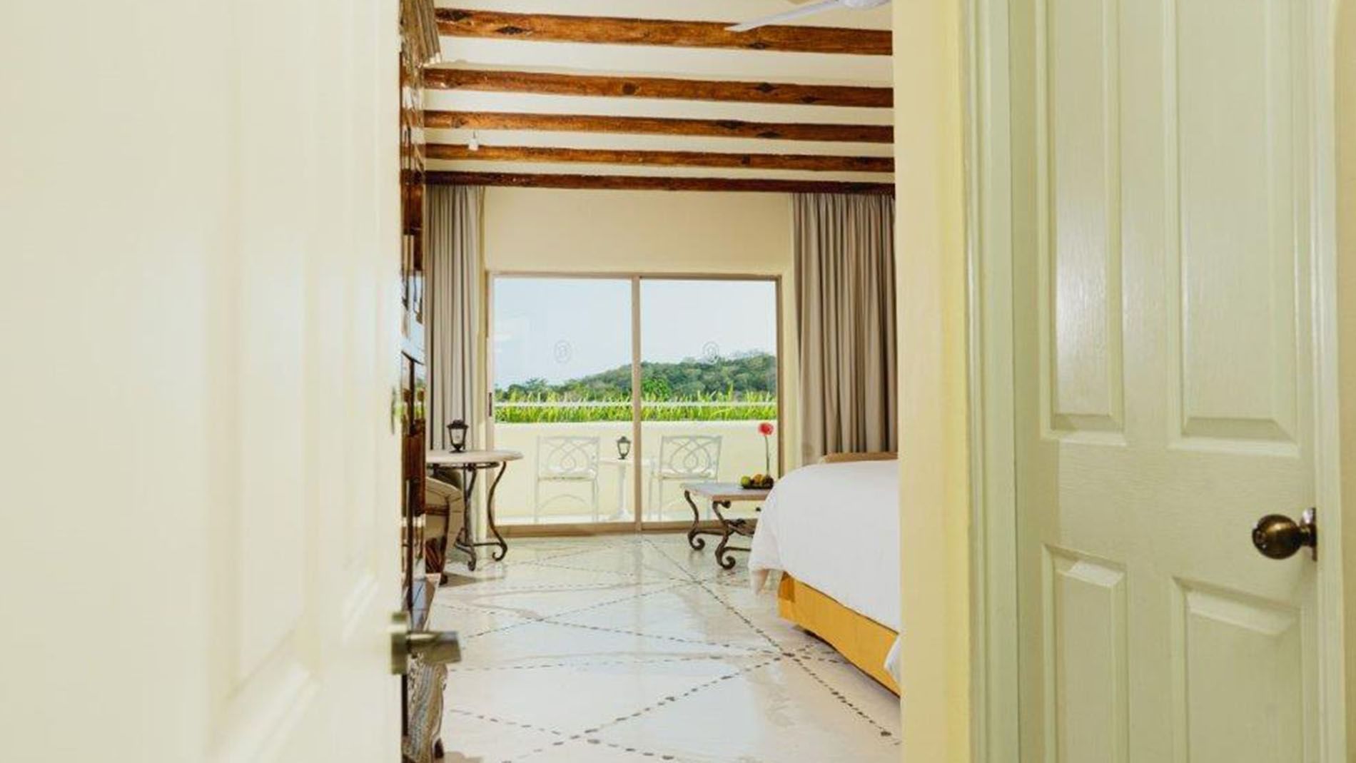 King Master Suite, showing a private balcony view and rustic wood beams on the ceiling at Quinta Real Huatulco