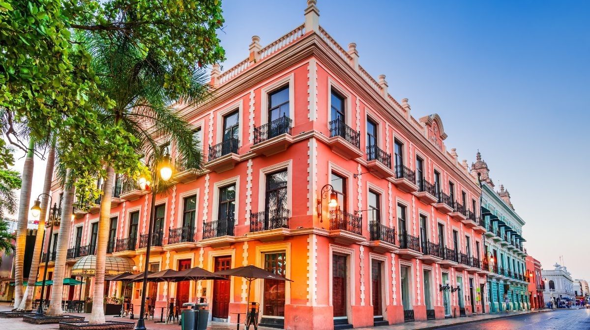Pink facade by tall palm trees under a blue sky surrounding a paved street at Camino Real Pedregal Mexico