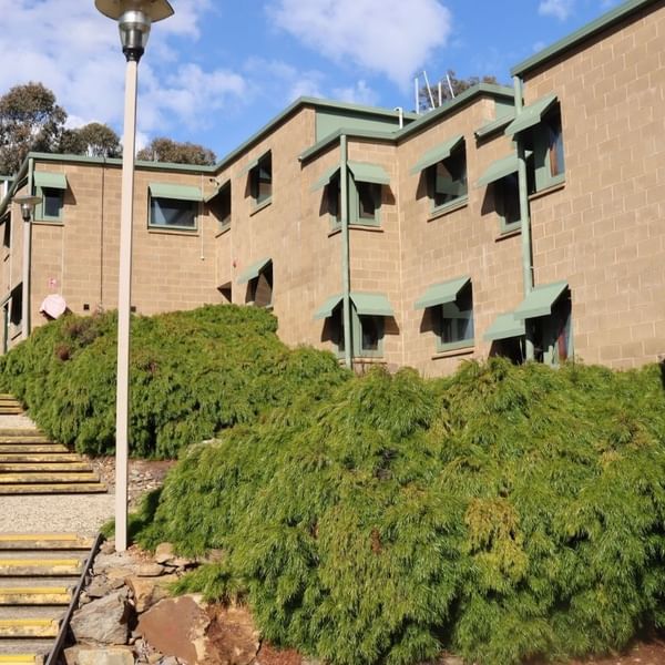 Staircase leading up to La Trobe University Units with green bushes and street lamps.