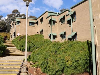 Staircase leading up to La Trobe University Units with green bushes and street lamps.