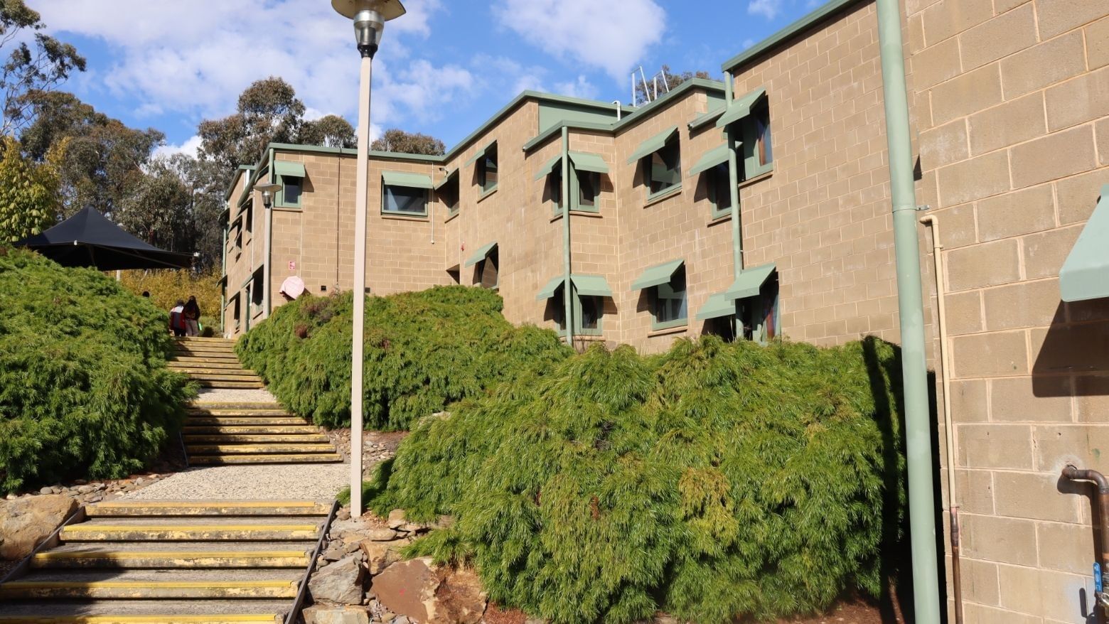 Staircase leading up to La Trobe University Units with green bushes and street lamps.