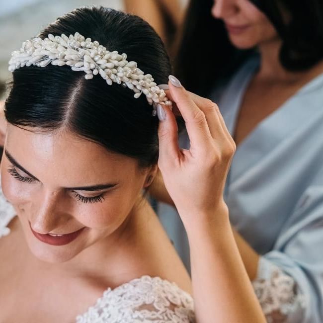 Bridesmaid putting headband on bride featuring our article on 