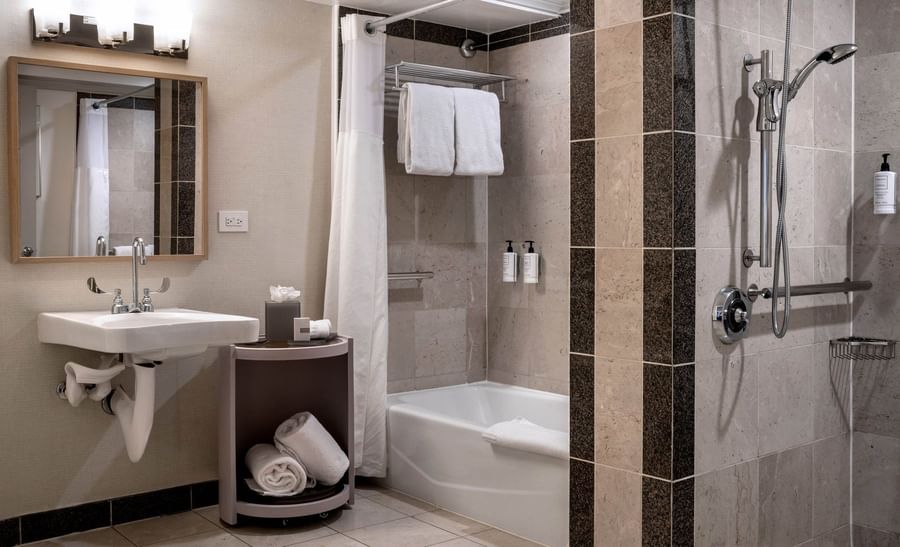 Modern bathroom with white towels by a bathtub under a shower curtain in Accessible Deluxe Rooms at Warwick Denver