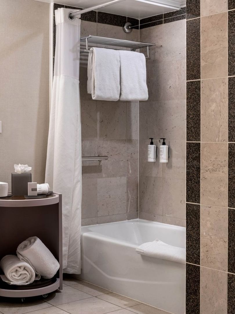 Modern bathroom with white towels by a bathtub under a shower curtain in Accessible Deluxe Rooms at Warwick Denver