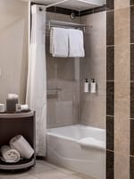 Modern bathroom with white towels by a bathtub under a shower curtain in Accessible Deluxe Rooms at Warwick Denver