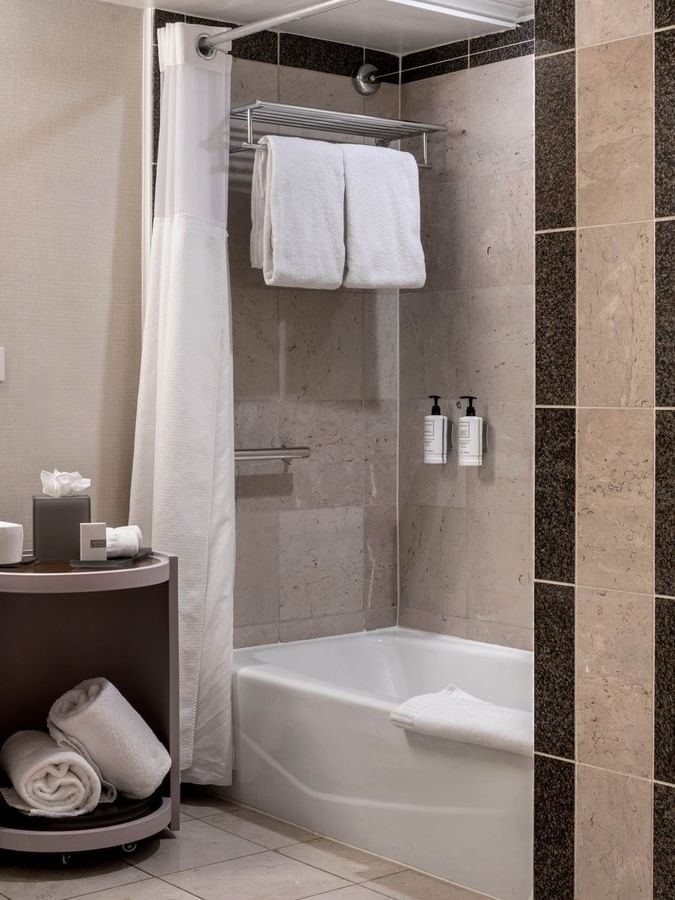 White towels by a bathtub in a modern bathroom under bright lights in Accessible Classic Rooms at Warwick Denver