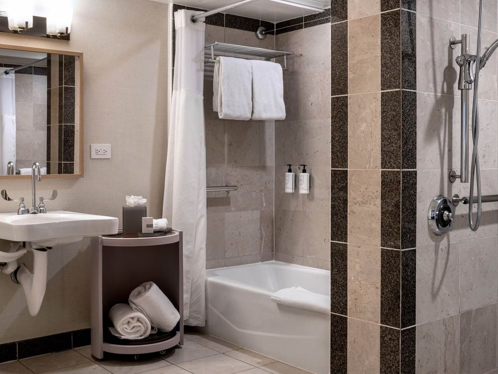 White towels by a bathtub in a modern bathroom under bright lights in Accessible Classic Rooms at Warwick Denver