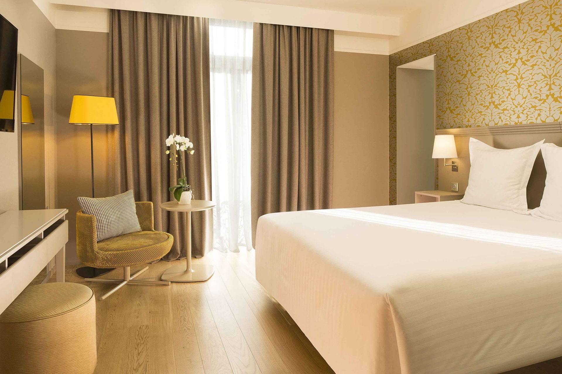 Lit queen-size et télévision dans une chambre Deluxe à l'Oceania Le Jura Dijon