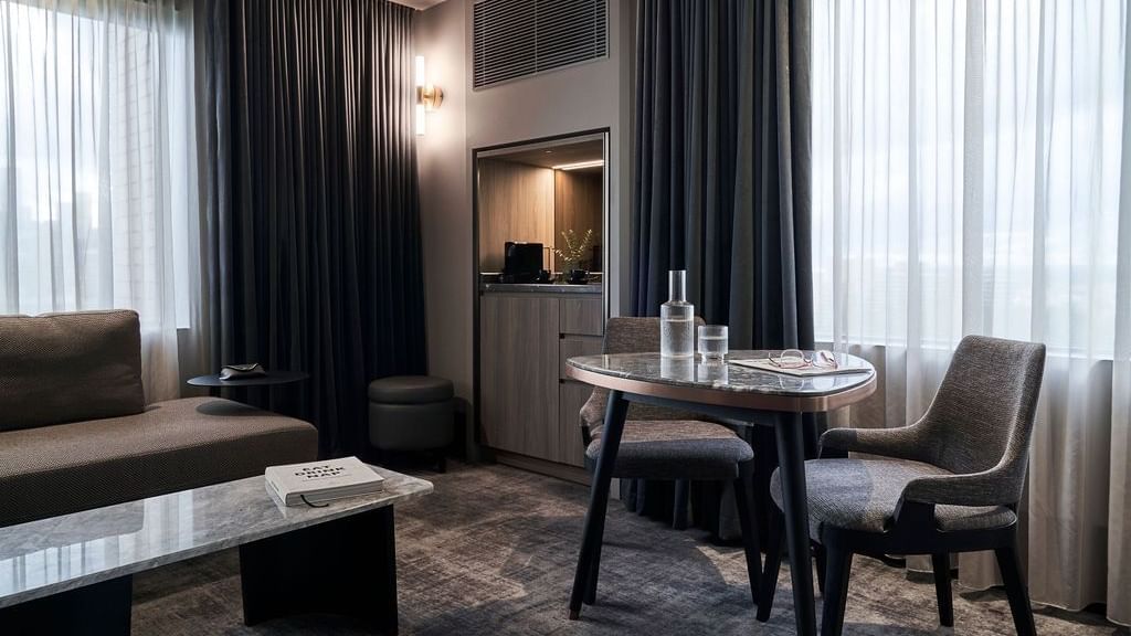 Modern suite with dining table, sofa, and  windows at Pullman East Melbourne