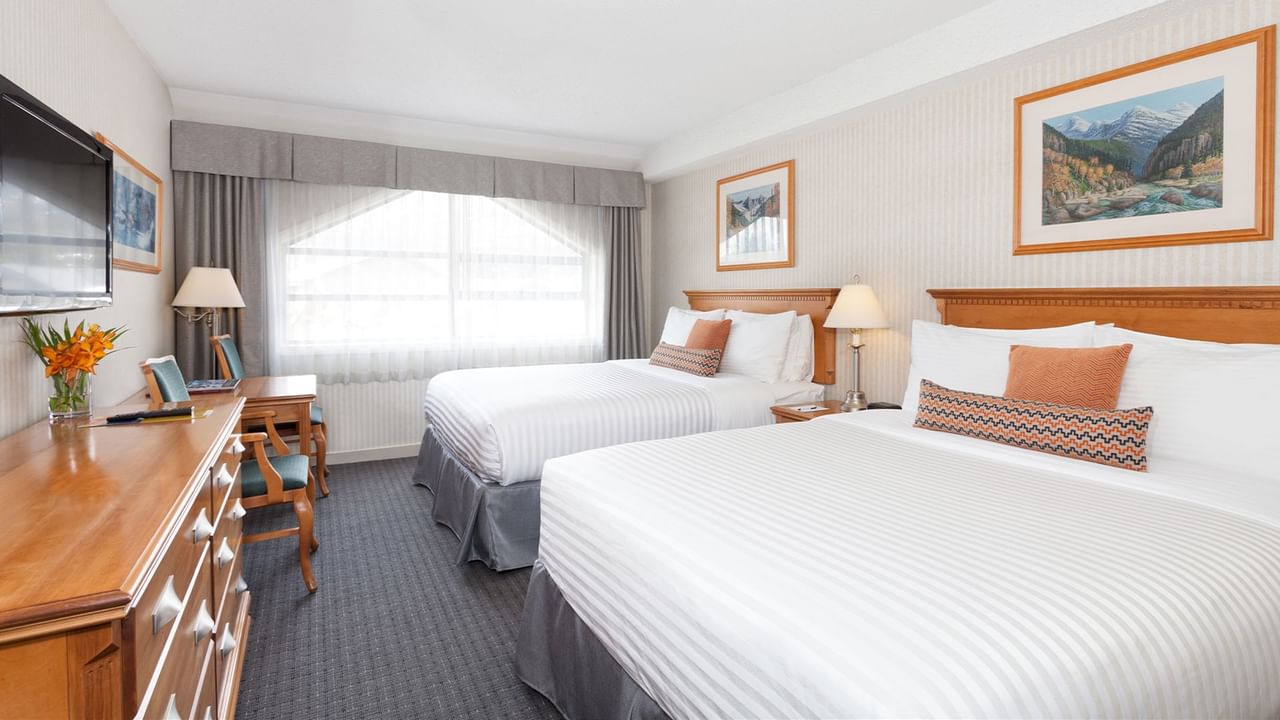 Spacious hotel room with two queen beds, elegant decor and large window for natural light.