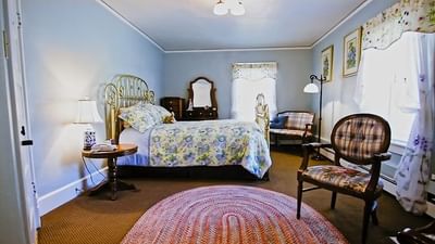 Dresser, cozy chairs, and nightstand by the bed in Ranch House Rooms with carpeted floors at The Ranch at UCross