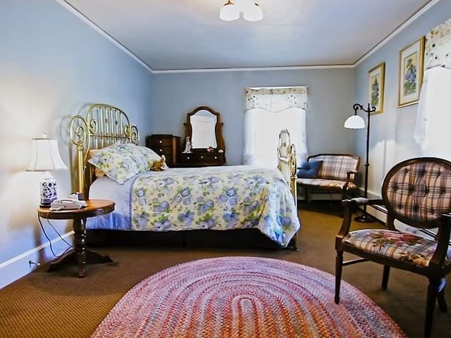 Dresser, cozy chairs, and nightstand by the bed in Ranch House Rooms with carpeted floors at The Ranch at UCross