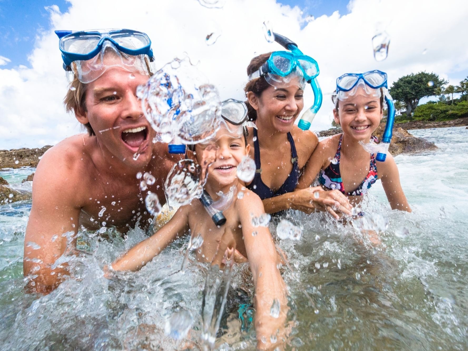 Family splashing water in the Sea with snorkeling equipment near Paradise Bay Resort