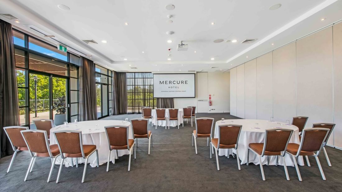 Kooindah Three conference room with tables, chairs, and large windows overlooking trees at Mercure Kooindah Waters