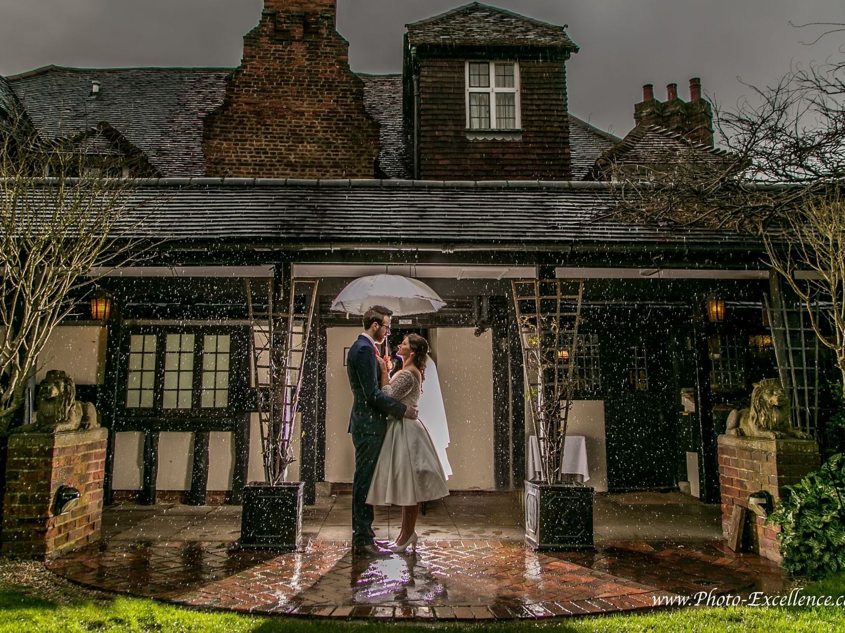 Romantic wedding photo near Marygreen Manor, showing the couple sharing a moment under an umbrella in the rain