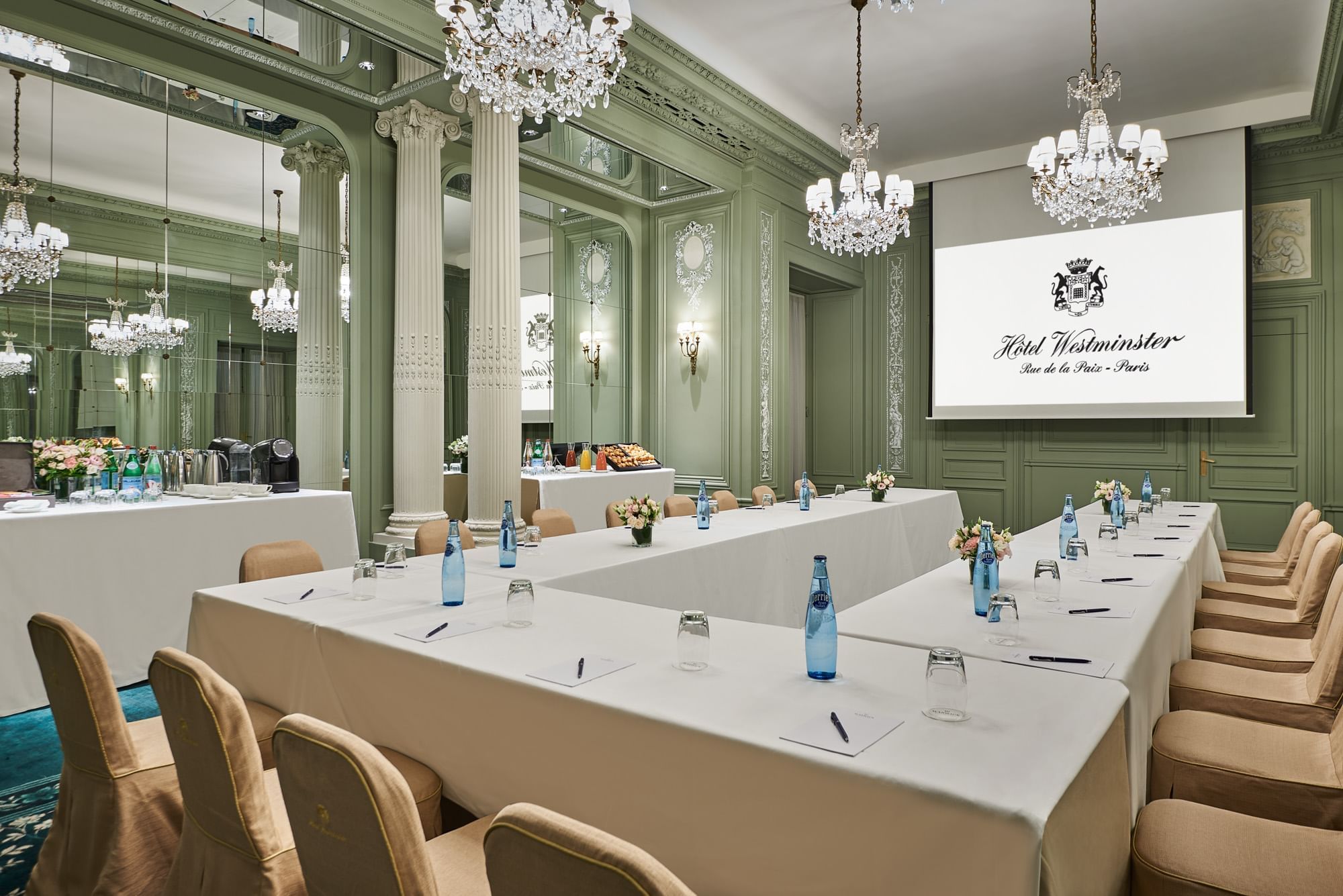 Interior of Récamier meeting room with U-shaped table set up, projector screen and a chandelier at Hôtel Westminster - Paris