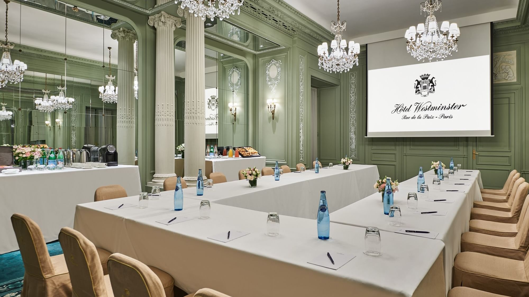 Interior of Récamier meeting room with U-shaped table set up, projector screen and a chandelier at Hôtel Westminster - Paris