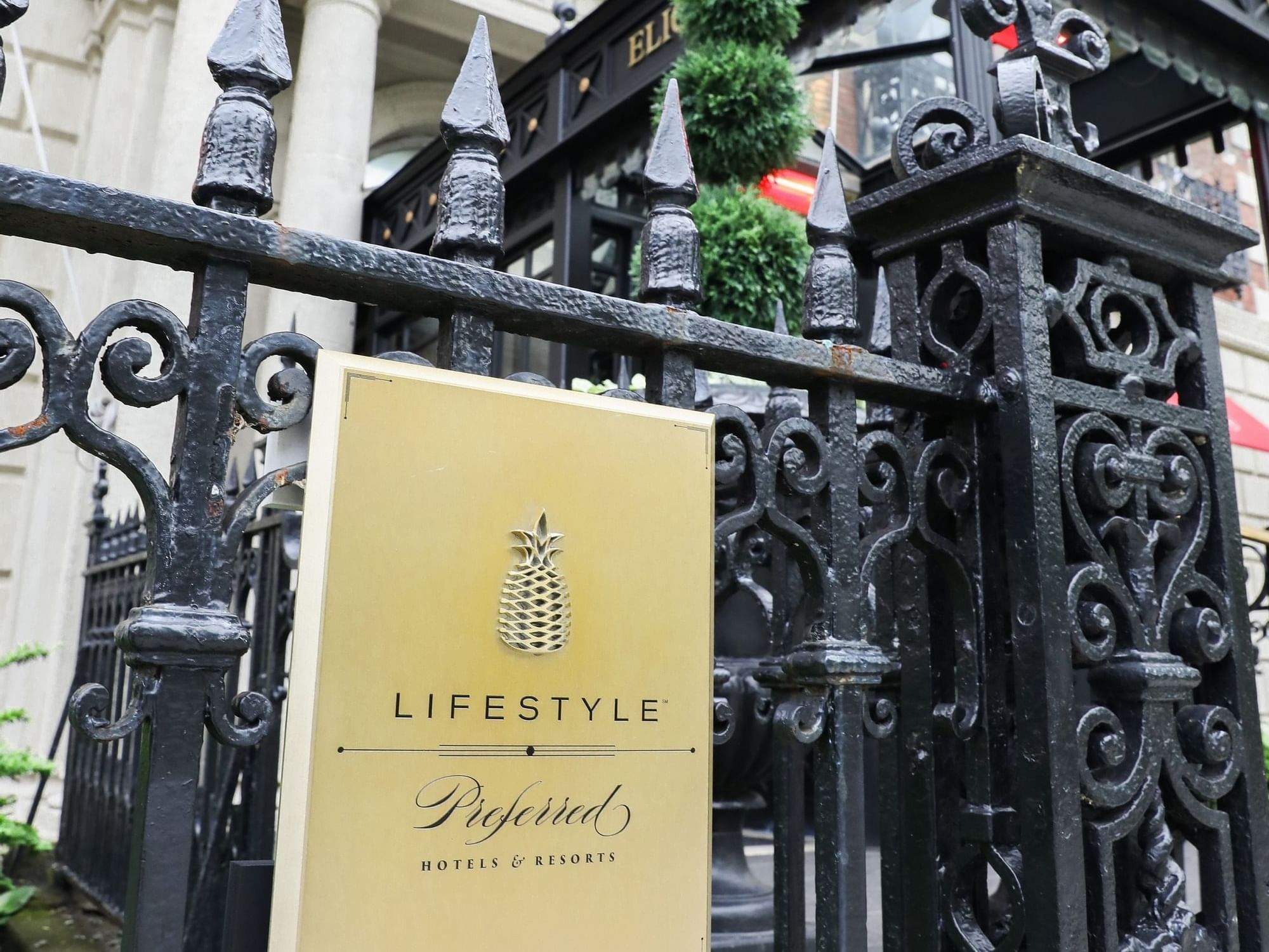 Closeup of signboard mounted on a black fence at Eliot Hotel