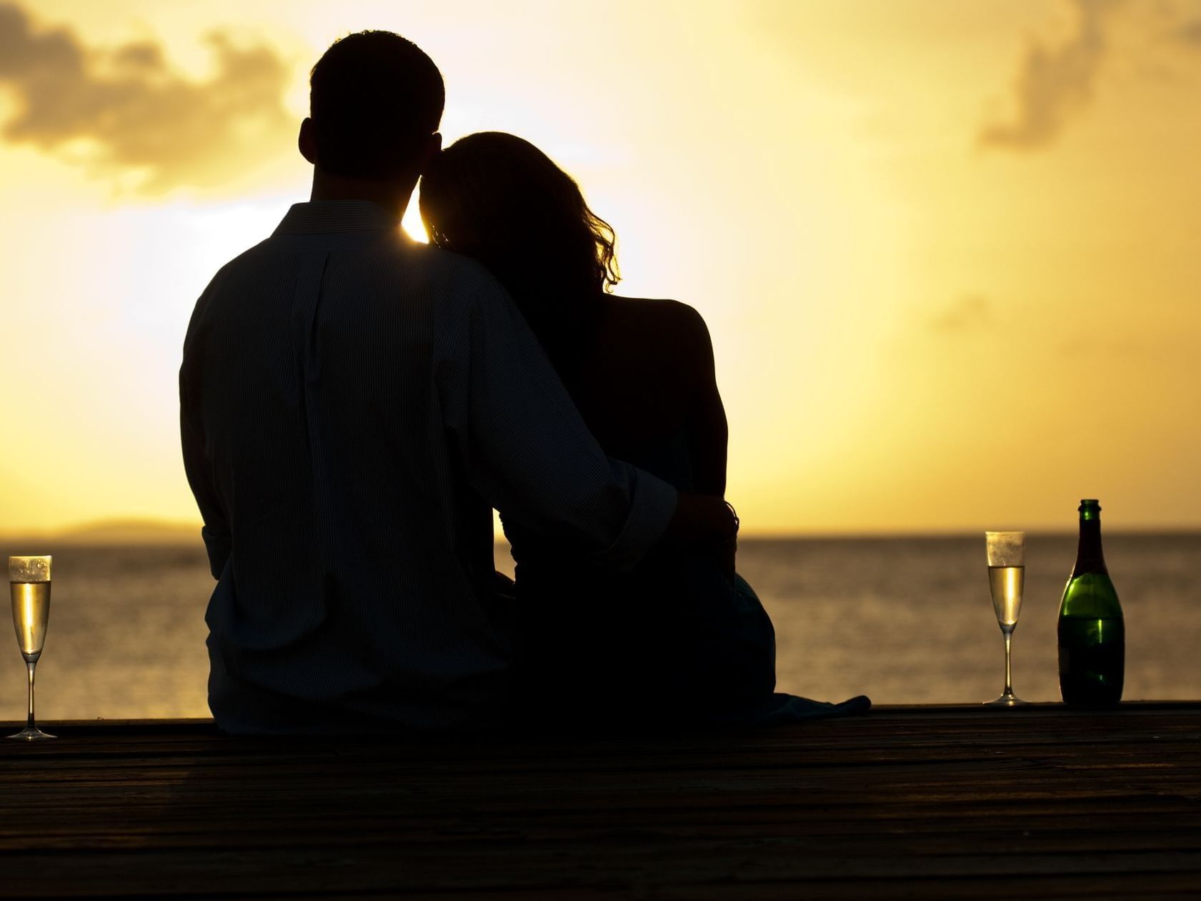 A couple seated on the beach near Buccaneer Hotel during sunset