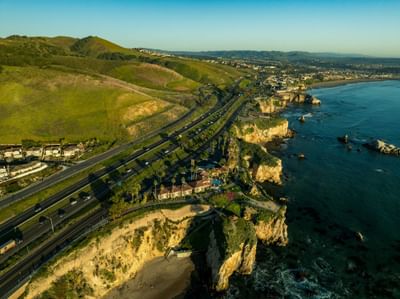 Aerial view of hotel and Pismo Preserve with green hills
