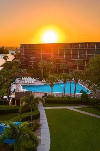 The exterior of Rosen Inn International and a pool at sunset. 