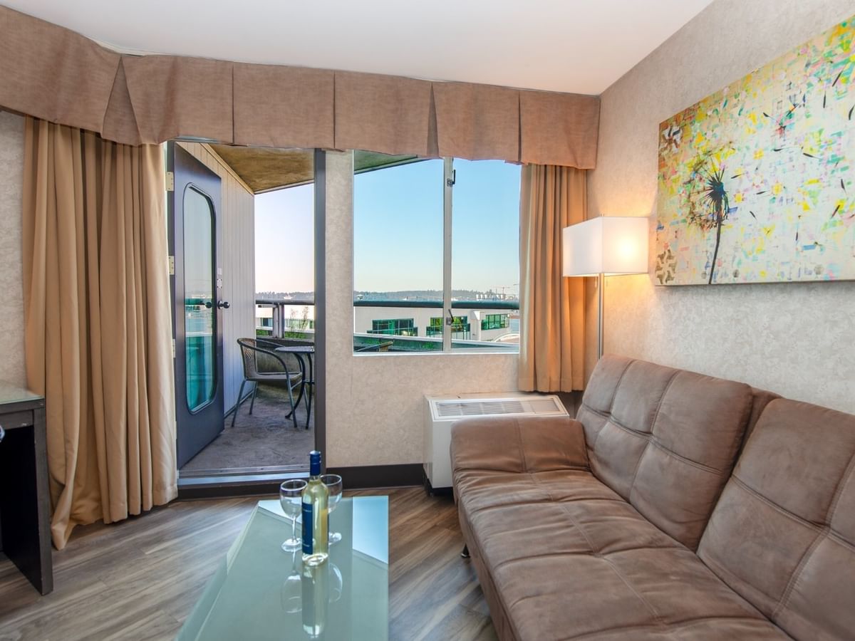 Coast Premium King with Patio with a couch, glass table, balcony, desk, and abstract painting at Coast Lonsdale Quay Hotel