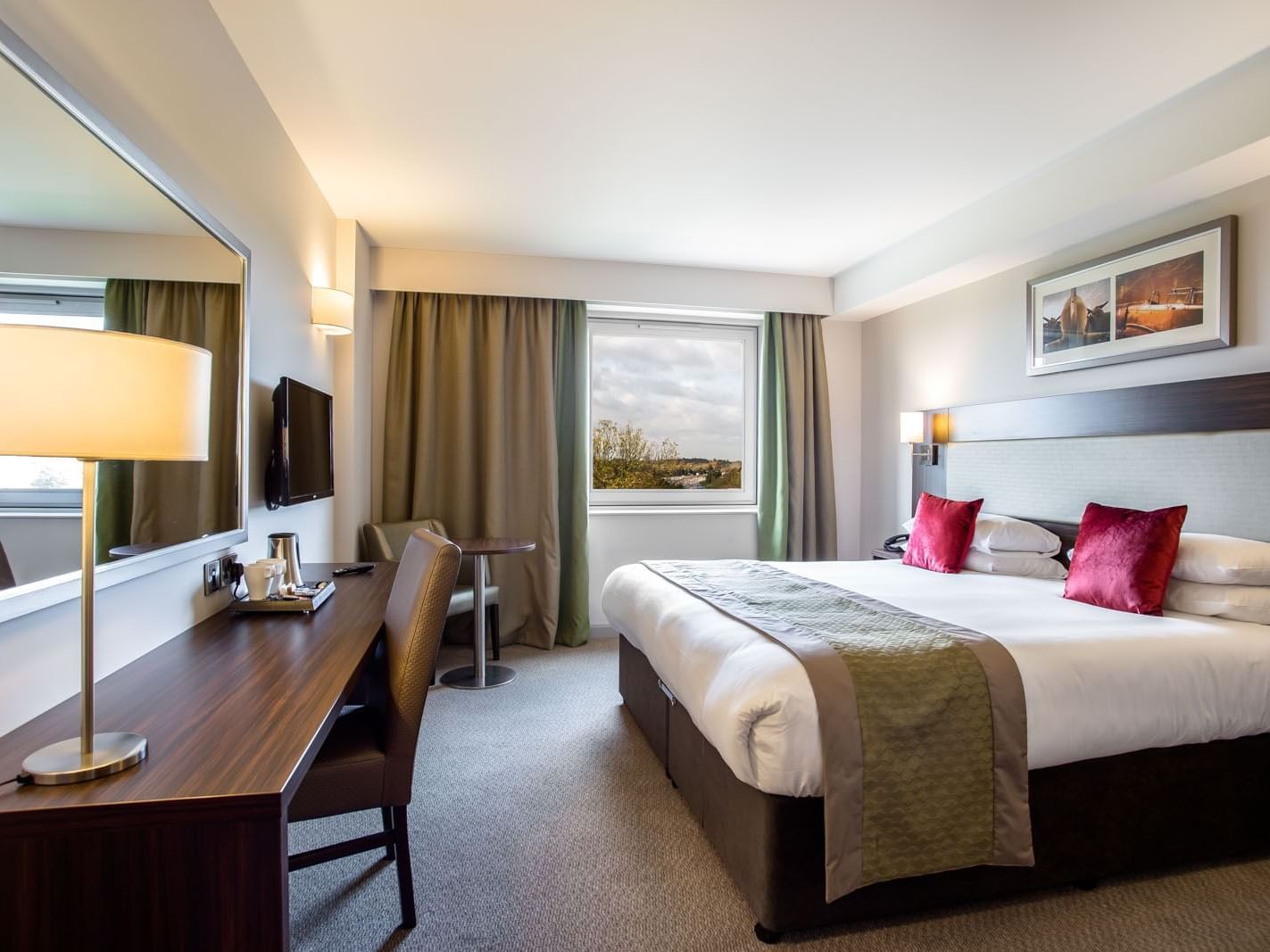 TV and work desk facing the bed by the window with carpet floors in Classic Double Room at Heston Hyde Hotel