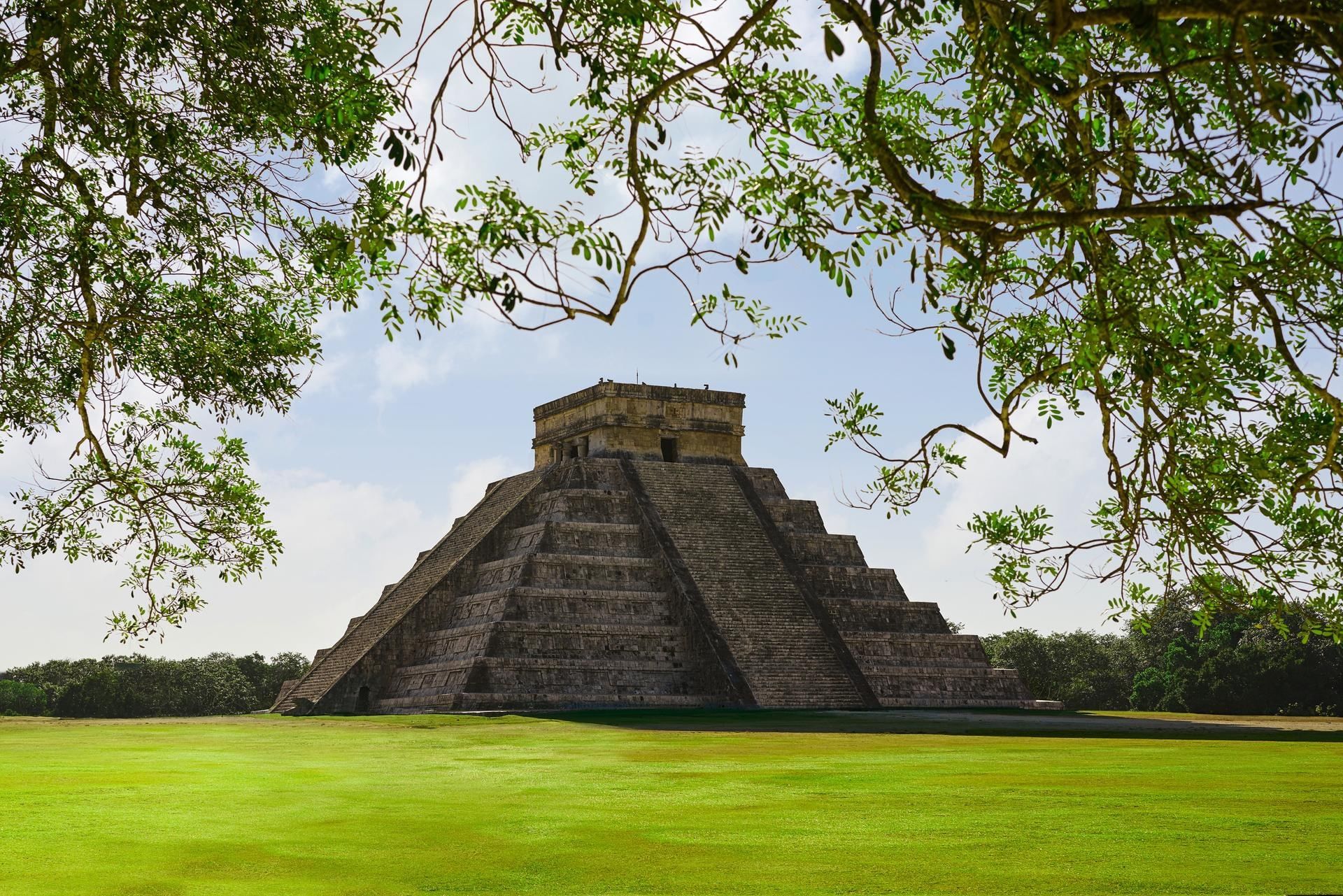 The Kukulcan pyramid at Chichen Itza framed by greenery on a day trip from Tulum.