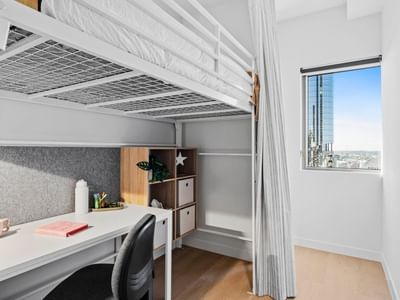Bunk bed, desk, and cityscape view in a room at UniLodge Brisbane City.