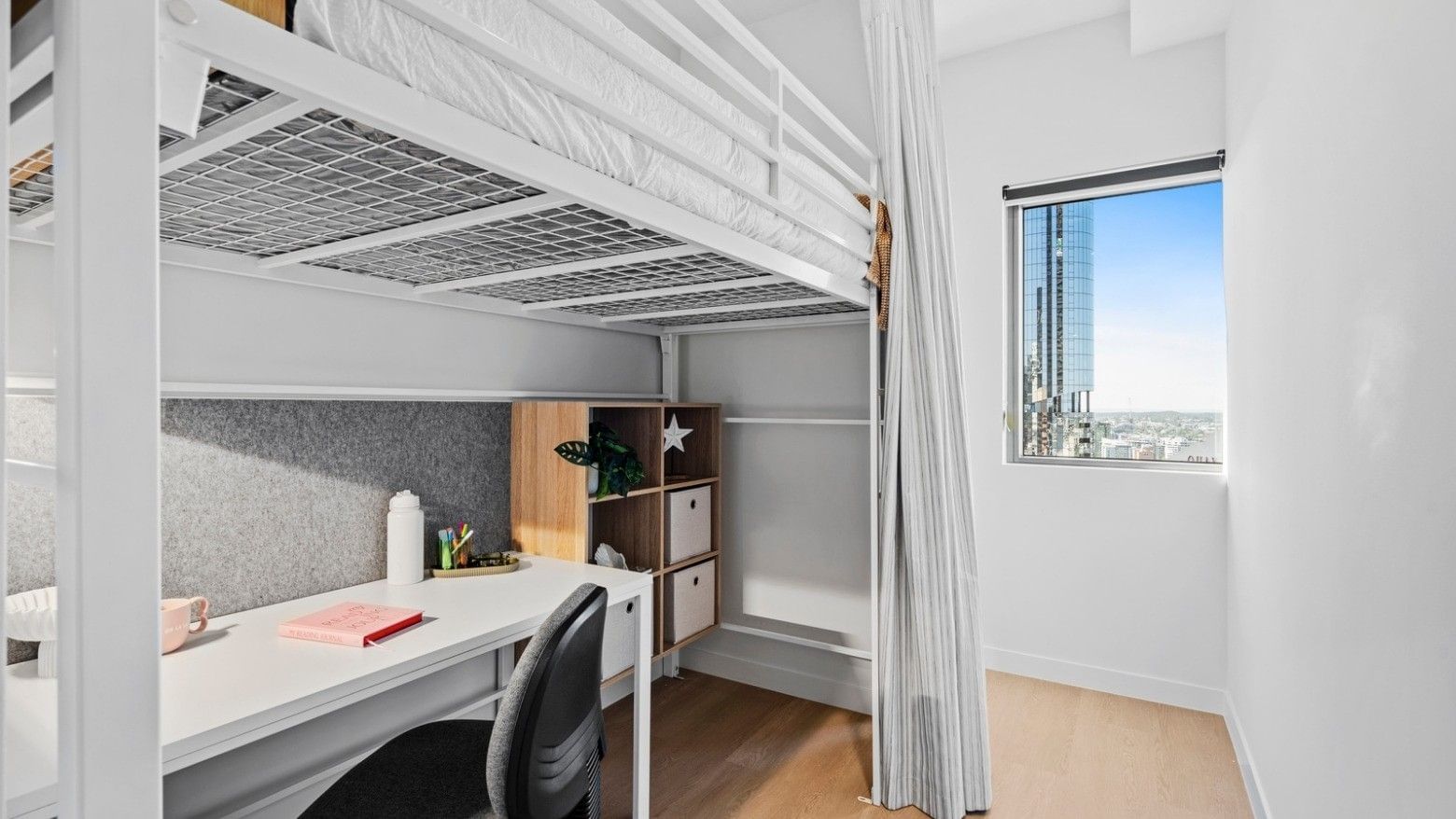 Bunk bed, desk, and cityscape view in a room at UniLodge Brisbane City.