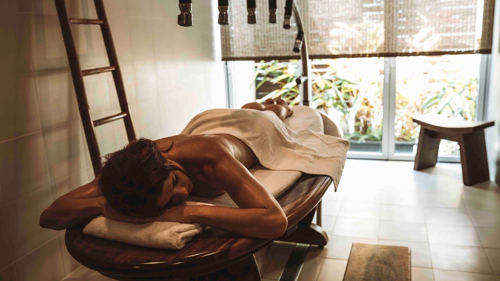 A woman relaxing on a massage bed in a spa at Pullman Cairns