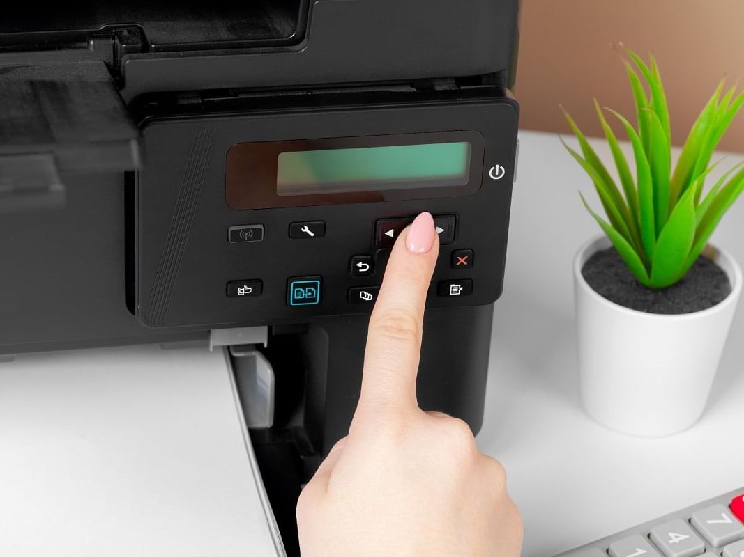 Close-up of hand pressing buttons on a printer at Nesuto St Martins