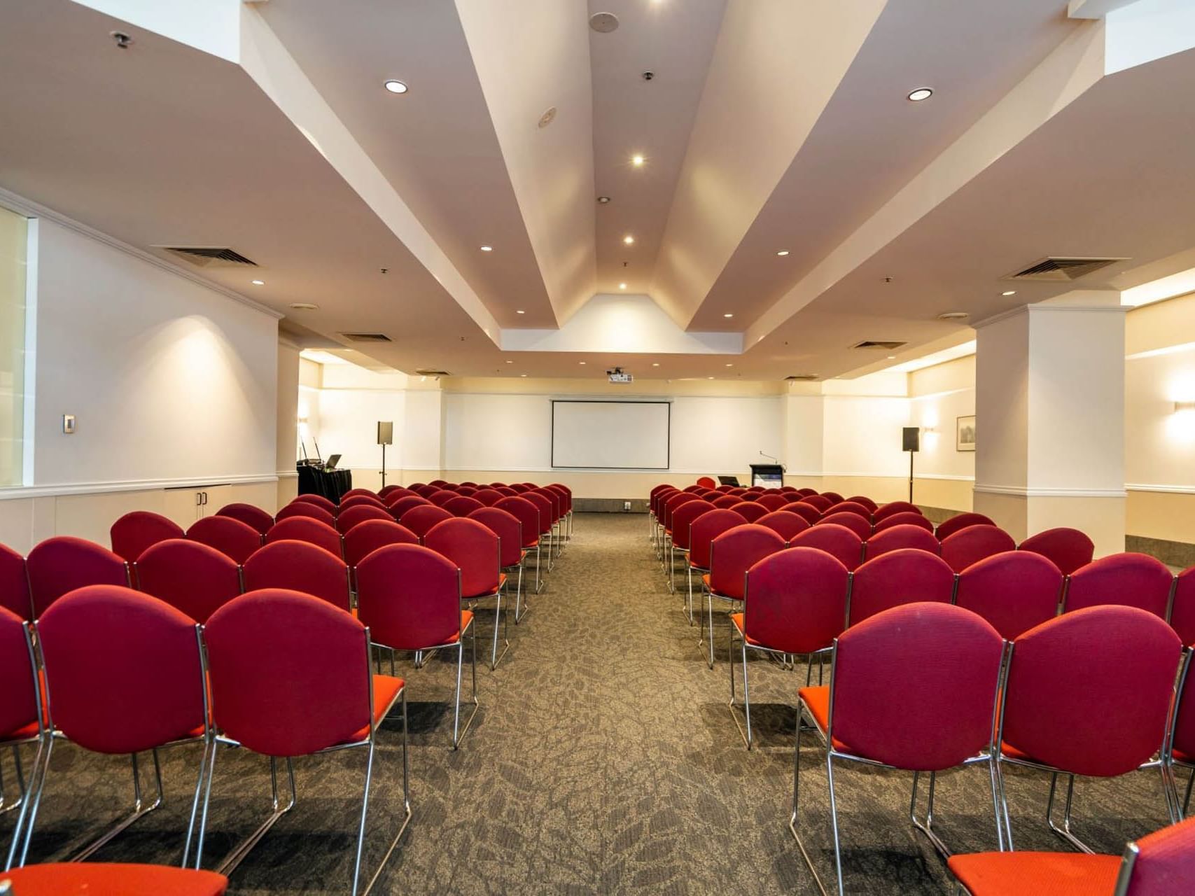 Theater set-up with shiraz color seats and a projector in Chancellor 6 at Hotel Grand Chancellor Hobart