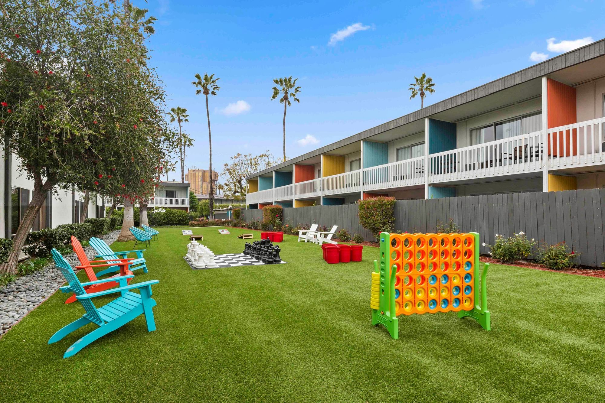 A colorful outdoor space with a lawn, trees, and various outdoor furniture and games.