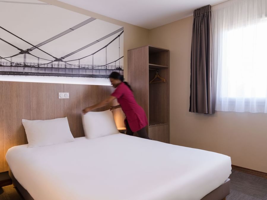 A Woman preparing a Standard Double bed at Hotel Ecoparc