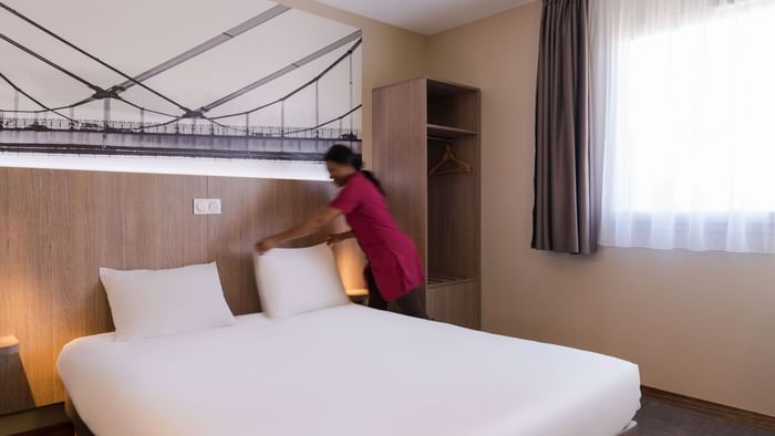 A Woman preparing a Standard Double bed at Hotel Ecoparc