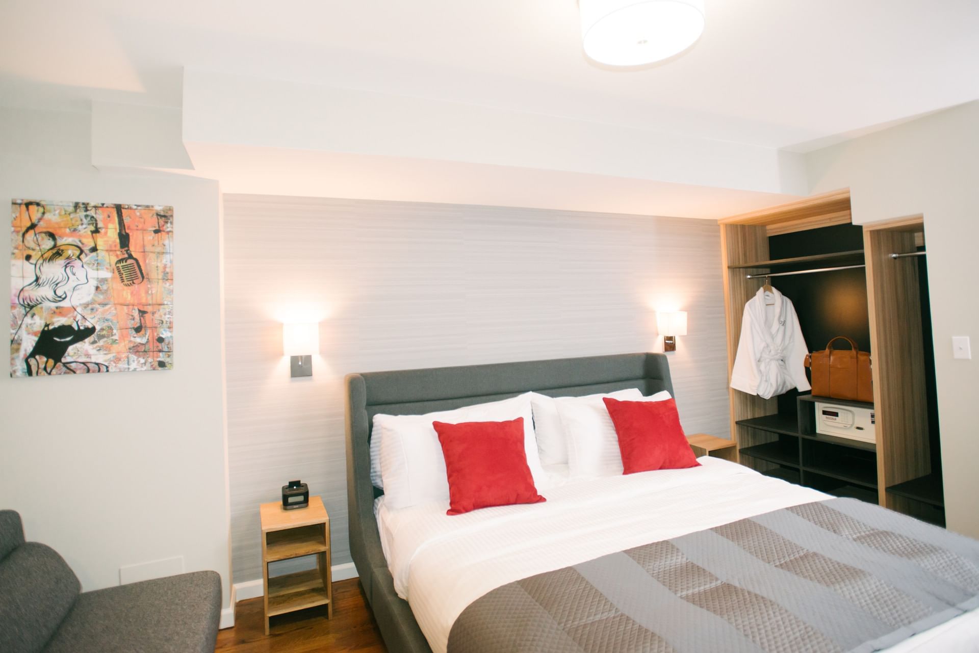 A hotel room with a bed, closet, nightstand, and sofa.
