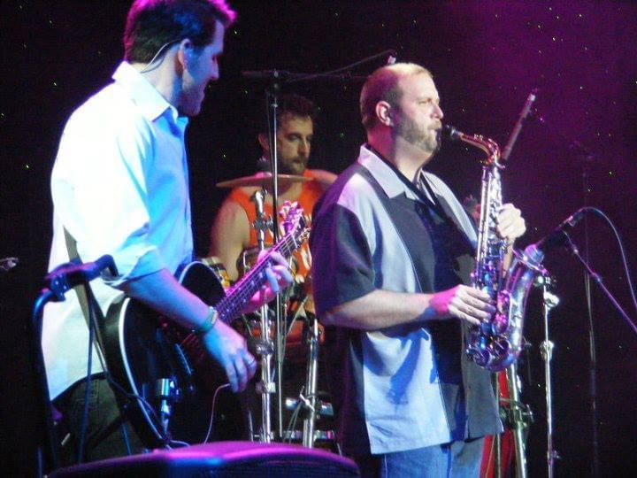 Man playing a saxaphone with a band