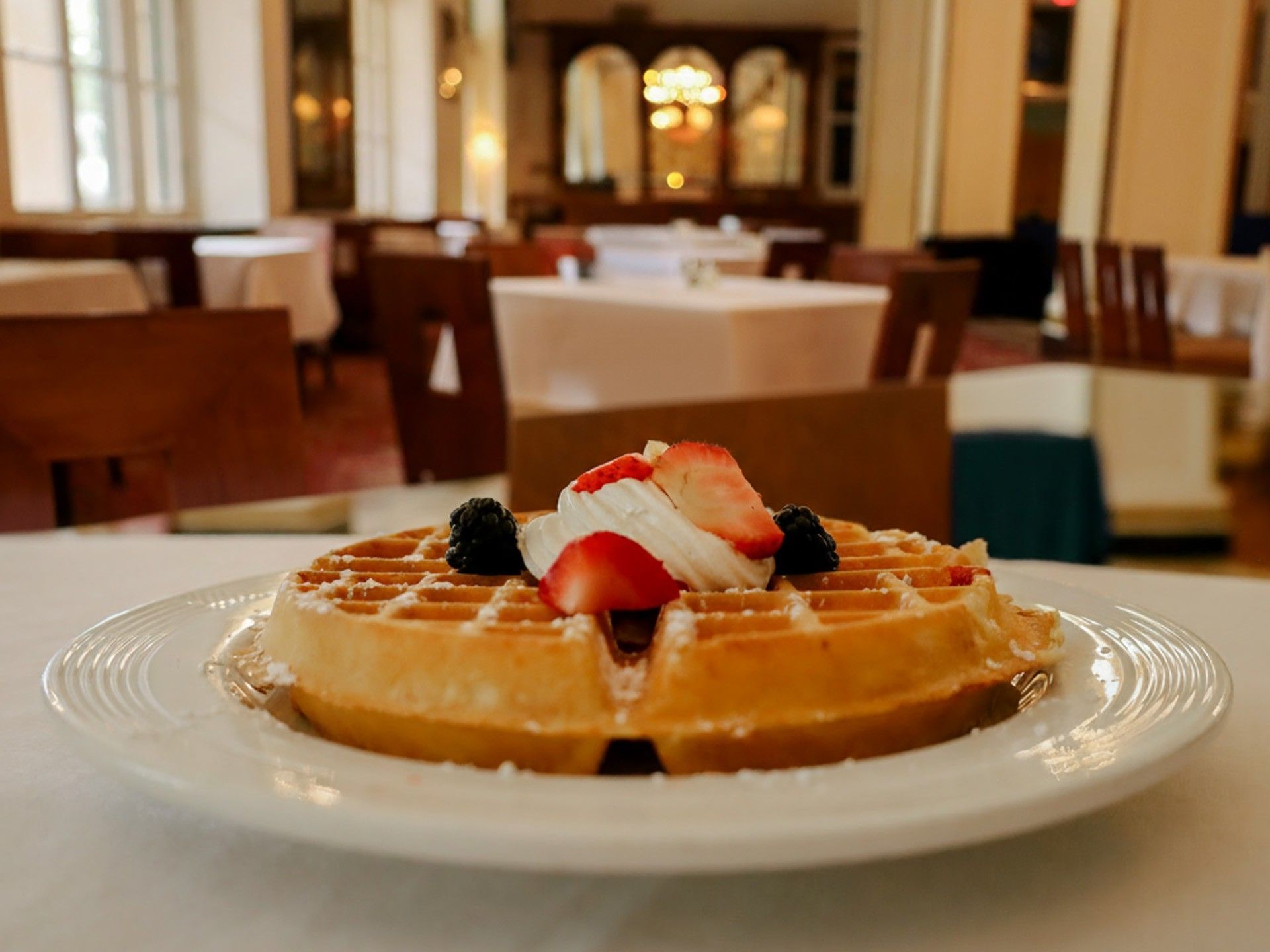 Delicious Belgian waffle topped with cream and berries, served for breakfast at Arlington Resort Hotel & Spa