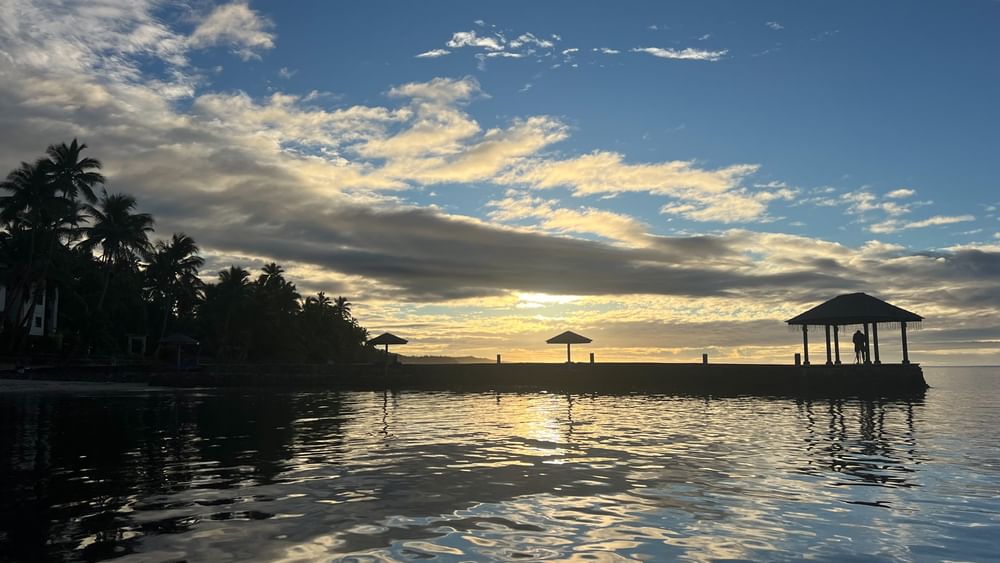 Sunset over serene waters and palm trees at Warwick Fiji Resort and Spa in Korolevu.