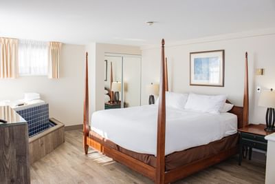 Four-poster bed by a tile tub under soft ceiling light at Rodd Brudenell River Resort, one of the best accommodations in PEI