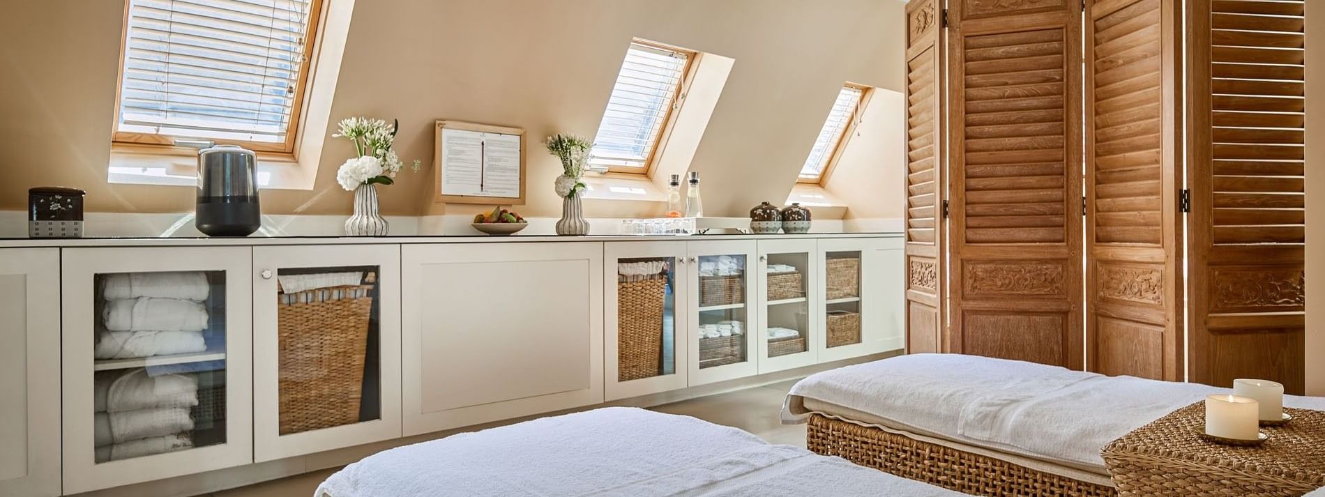 Spa treatment area, with massage tables by white cabinets, under a sloped wooden ceiling at Hotel Westminster Paris