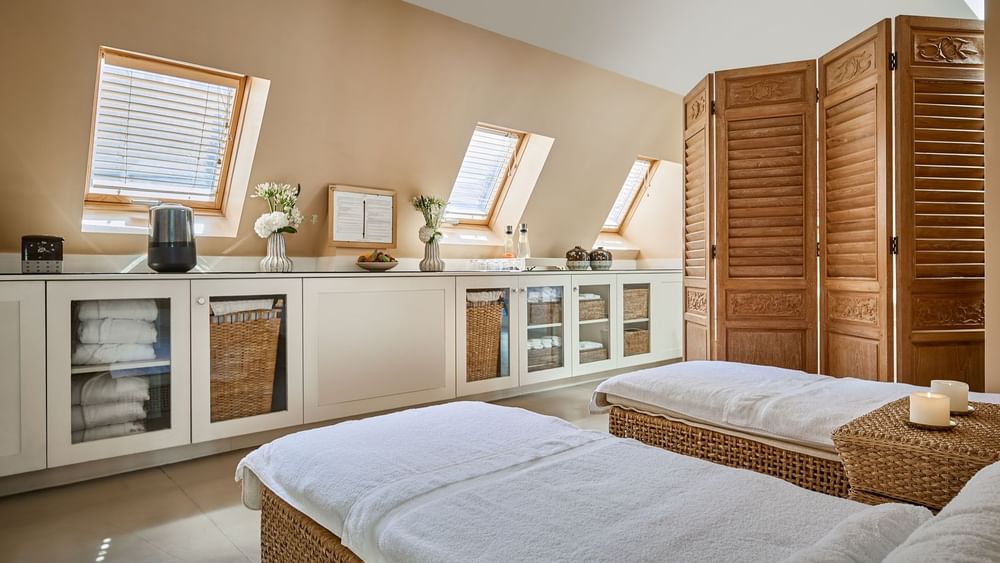 Spa treatment area, with massage tables by white cabinets, under a sloped wooden ceiling at Hotel Westminster Paris