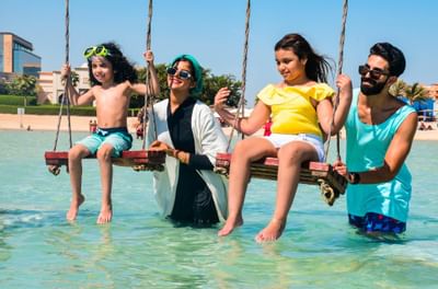 A family in the swings at the beach near Bay La Sun Hotel & Marina