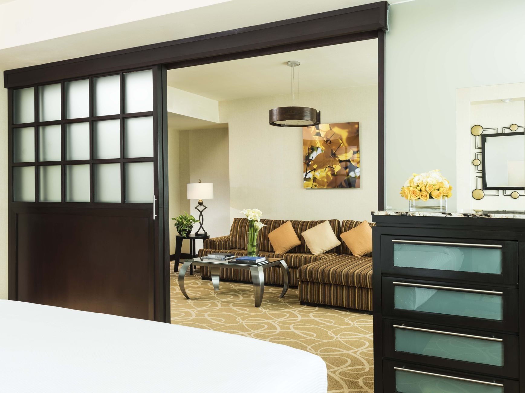 Suite Junior con cama grande, sofá cama, mesa y flores en el Marquis Reforma de Ciudad de México.