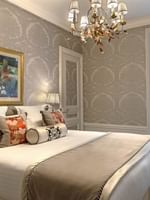 Élégante chambre Deluxe avec un grand lit, du papier peint à motifs et une vue sur Paris à l'Hôtel Westminster - Paris.