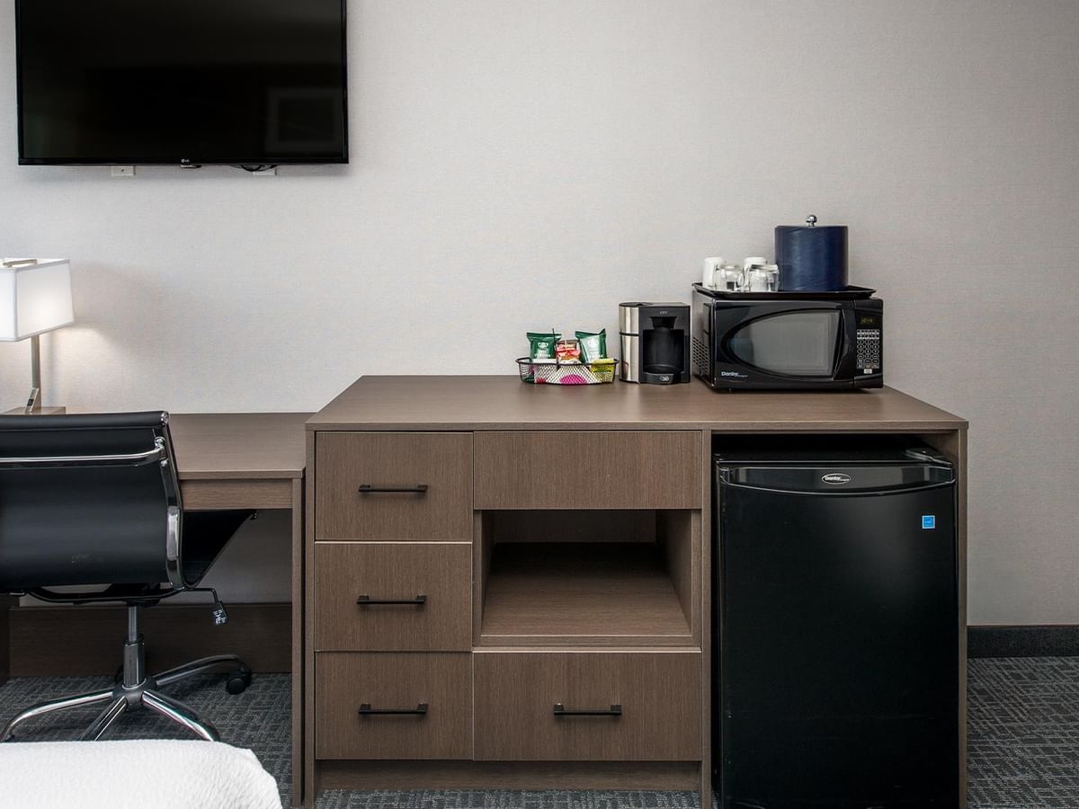 Work desk, chair, microwave, and fridge.