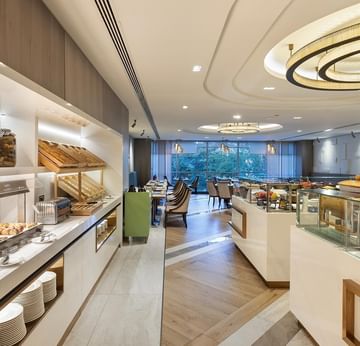 A buffet area with various food dishes, jars, plates, and a circular ceiling light in the dining hall  in Alesta Restaurant at Titanic Port Bakırköy