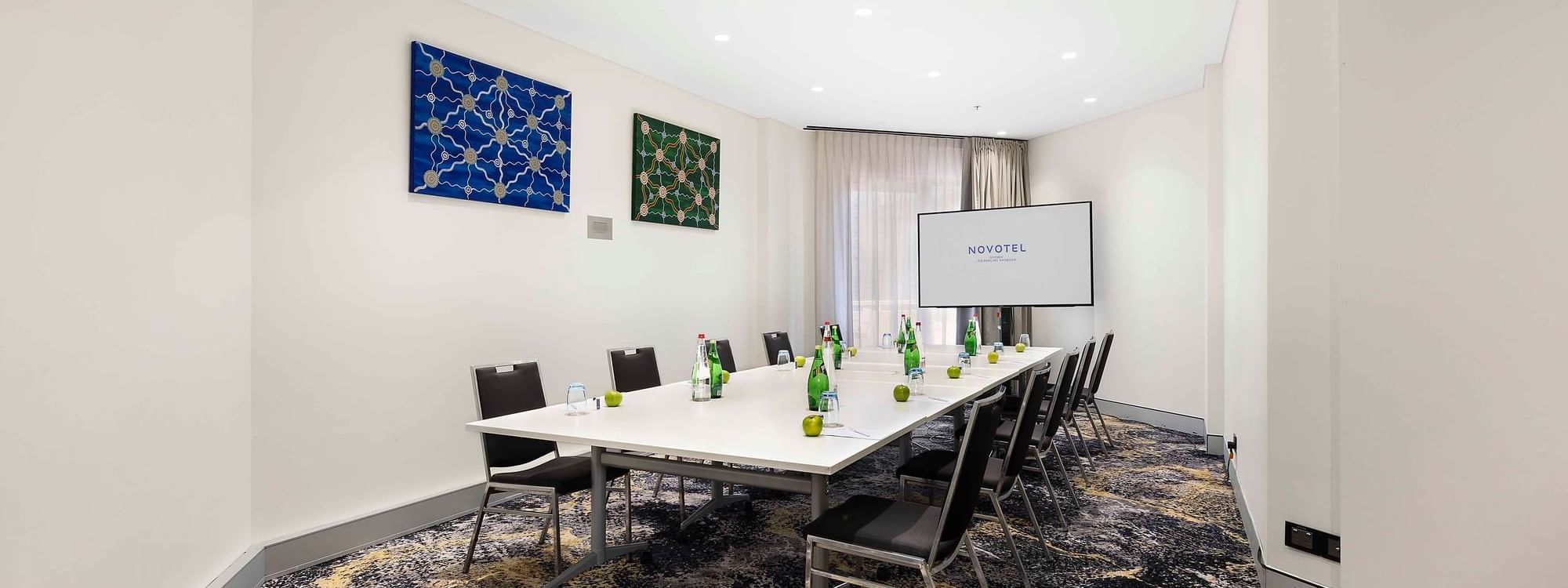 Boardroom set-up facing the projector screen in The Hastings Boardroom at Novotel Sydney on Darling Harbour