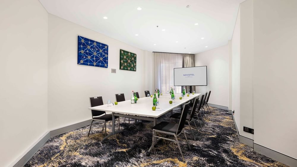 Boardroom set-up facing the projector screen in The Hastings Boardroom at Novotel Sydney on Darling Harbour